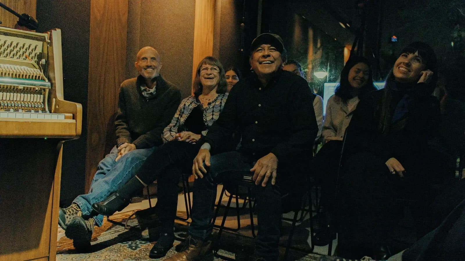 Audience laughing beside an opened upright piano at an Andante Piano night