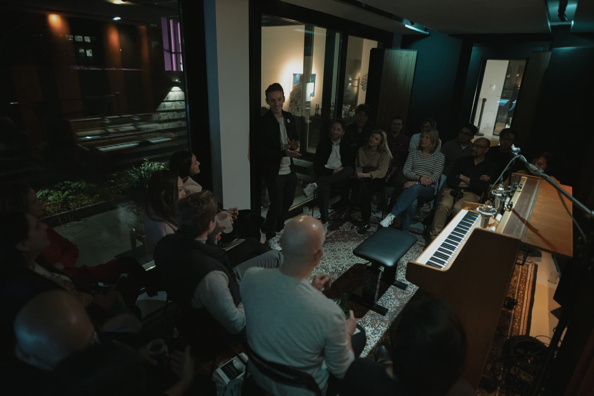 Ivo Adelaar hosting an evening, talking to an audience seated around the piano in the studio