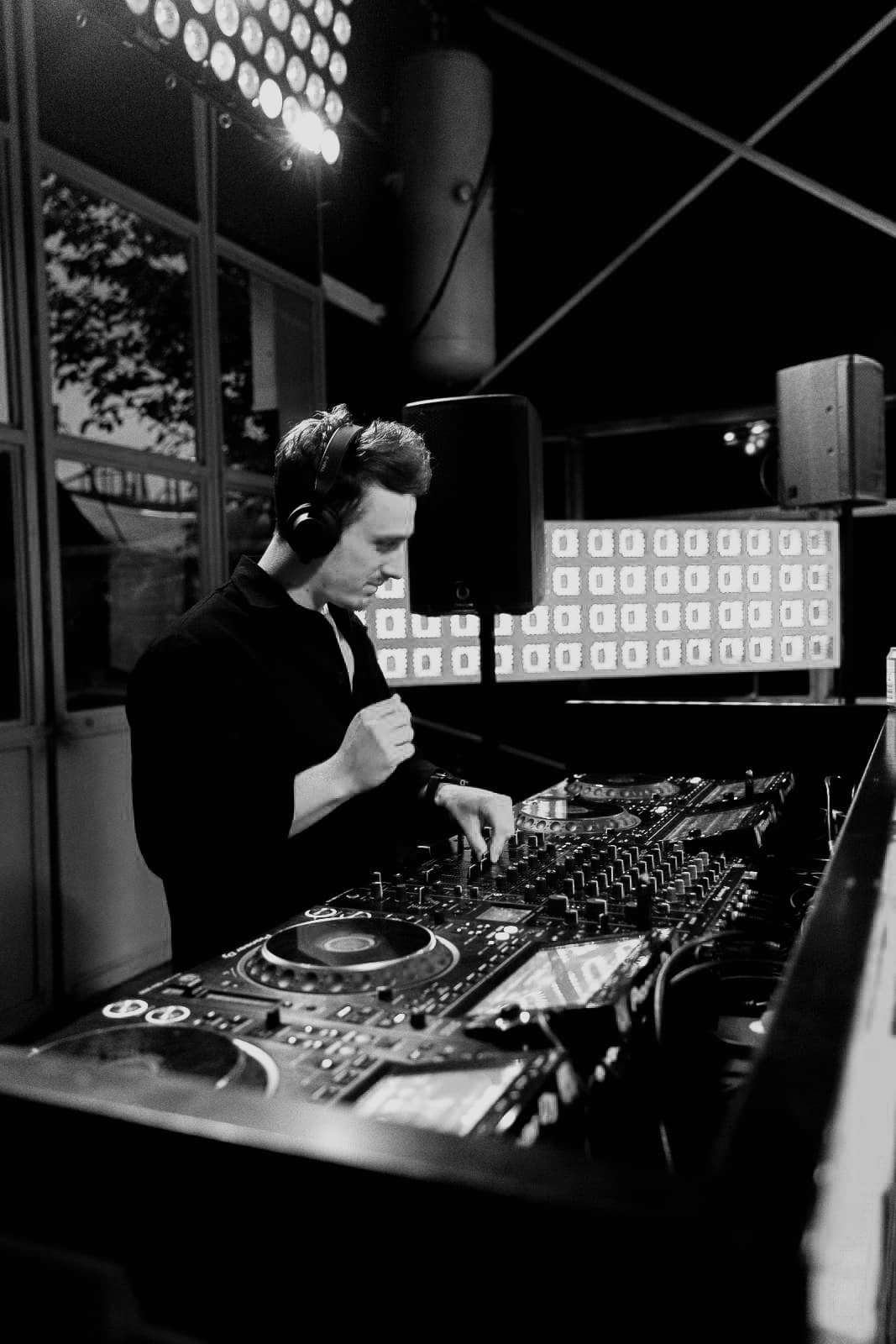 Ivo Adelaar mixing at the decks in black and white, headphones on