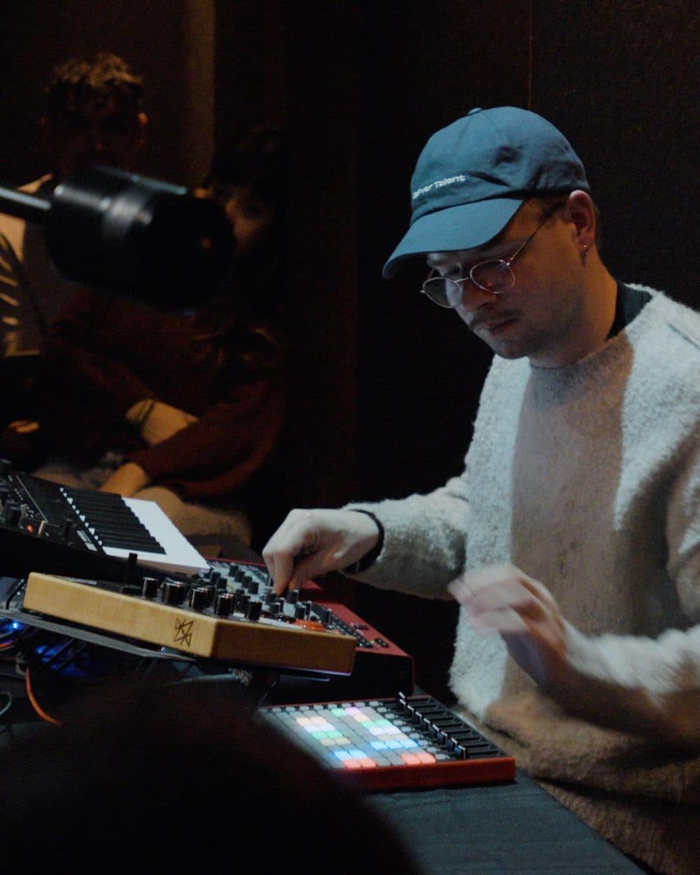 An artist bent over synthesizers and a drum machine during a Disruptive Records studio session